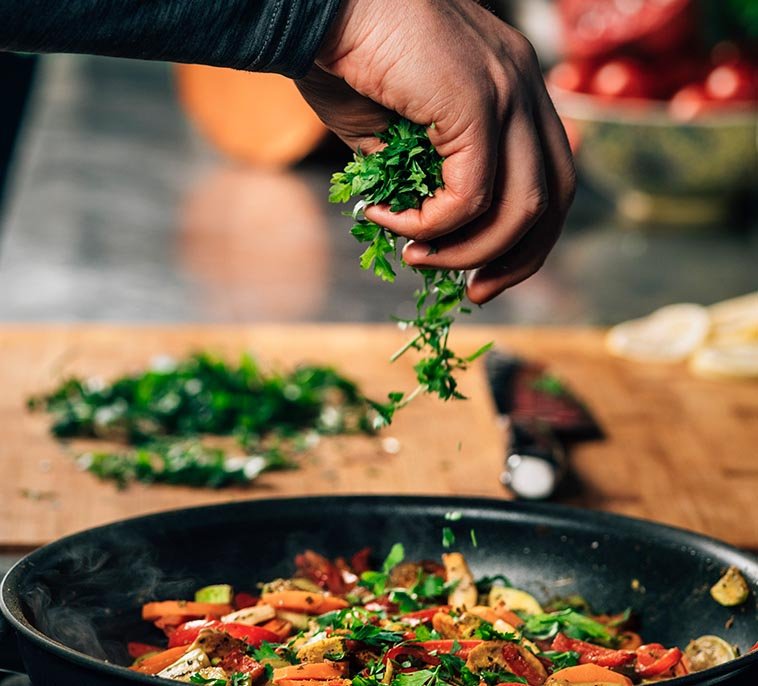 hand adding parsley into frying pan with vegetable 2021 08 27 09 01 22 utc2